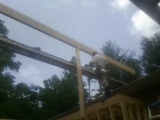 Carpenter setting a ridge beam over a new addition frame — Ice Dam Removal by Roofing Brothers in Swan