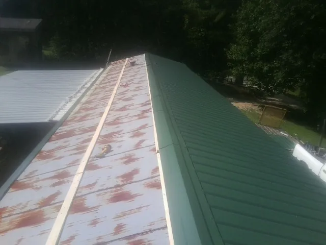 Old rusted panels beside newly installed green metal roofing — Wind Damage Roof Repair by Roofing Brothers in Swan