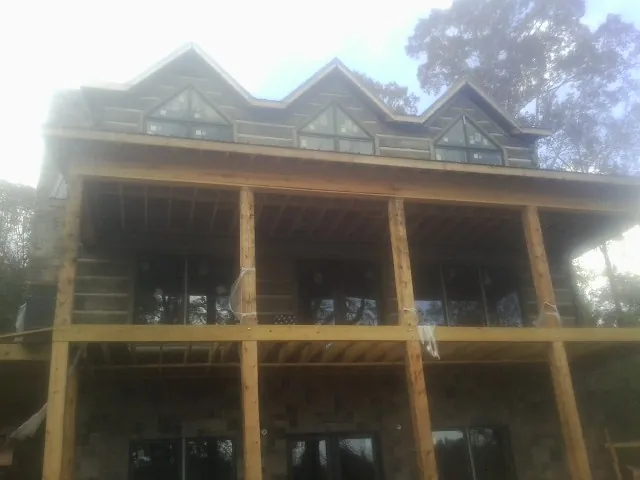 Dormers and porch framing on a large log home under construction — Roof Coating work by our crew in Swan