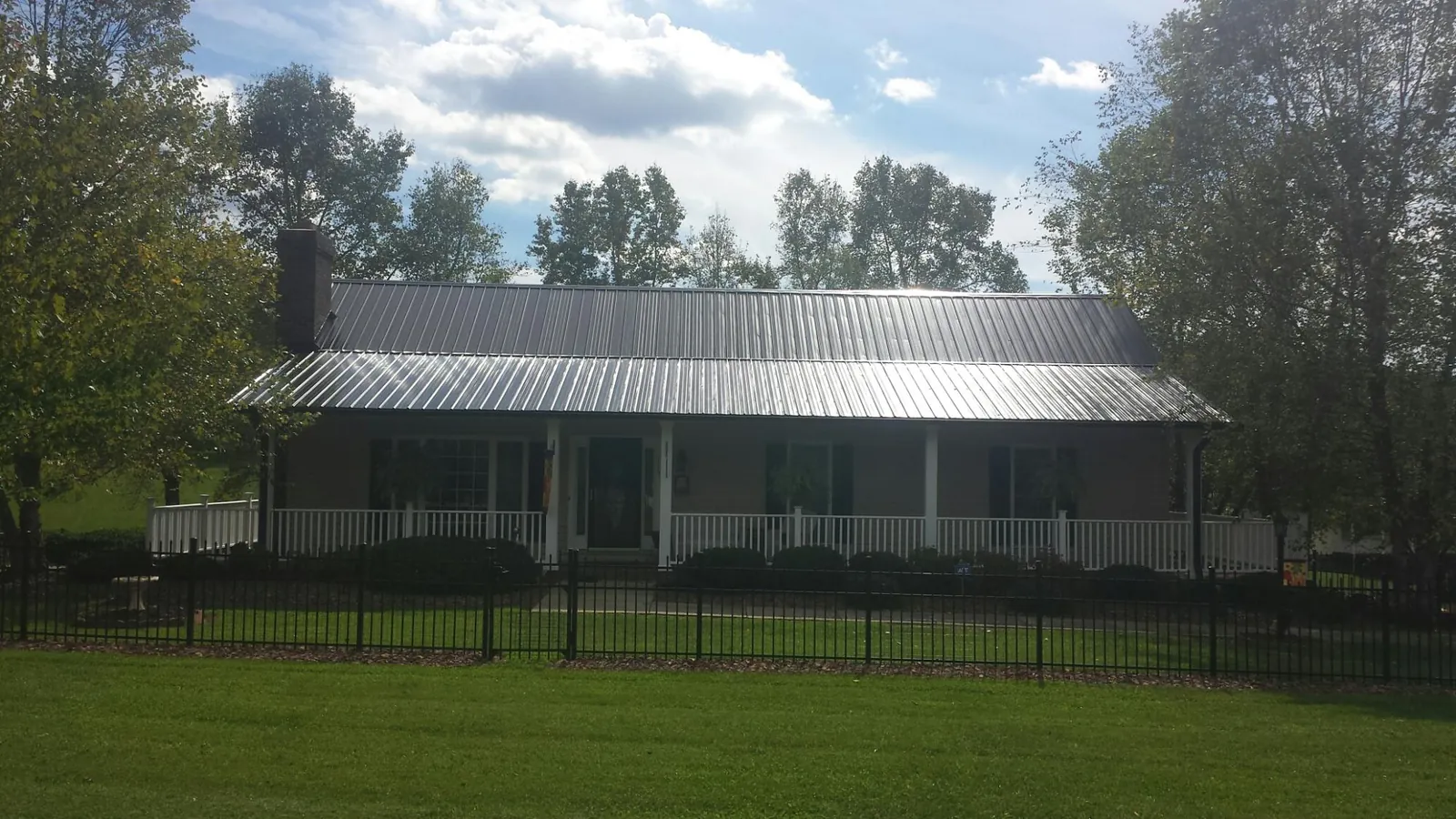 Gray metal roof on a brick ranch with a full width front porch — Gutter Guard Installation work by our crew in Swan