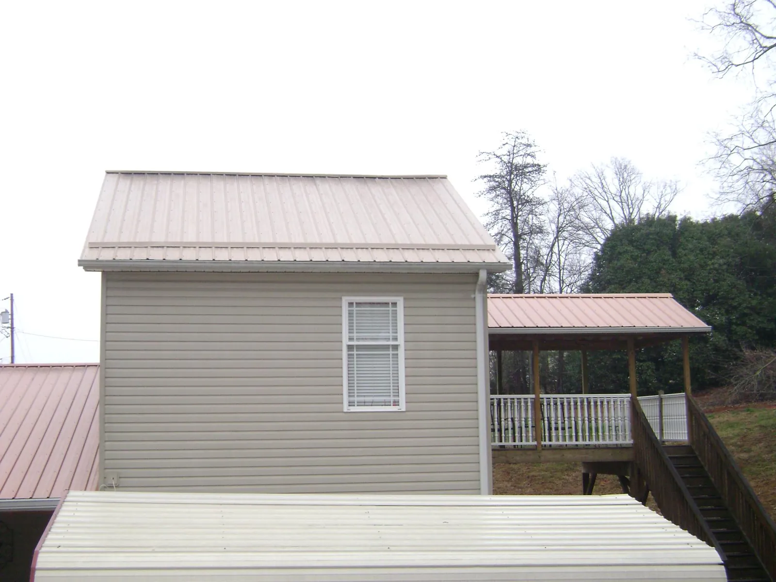 Tan metal roofs on a two story addition and attached porch, from a Roof Replacement job in Swan