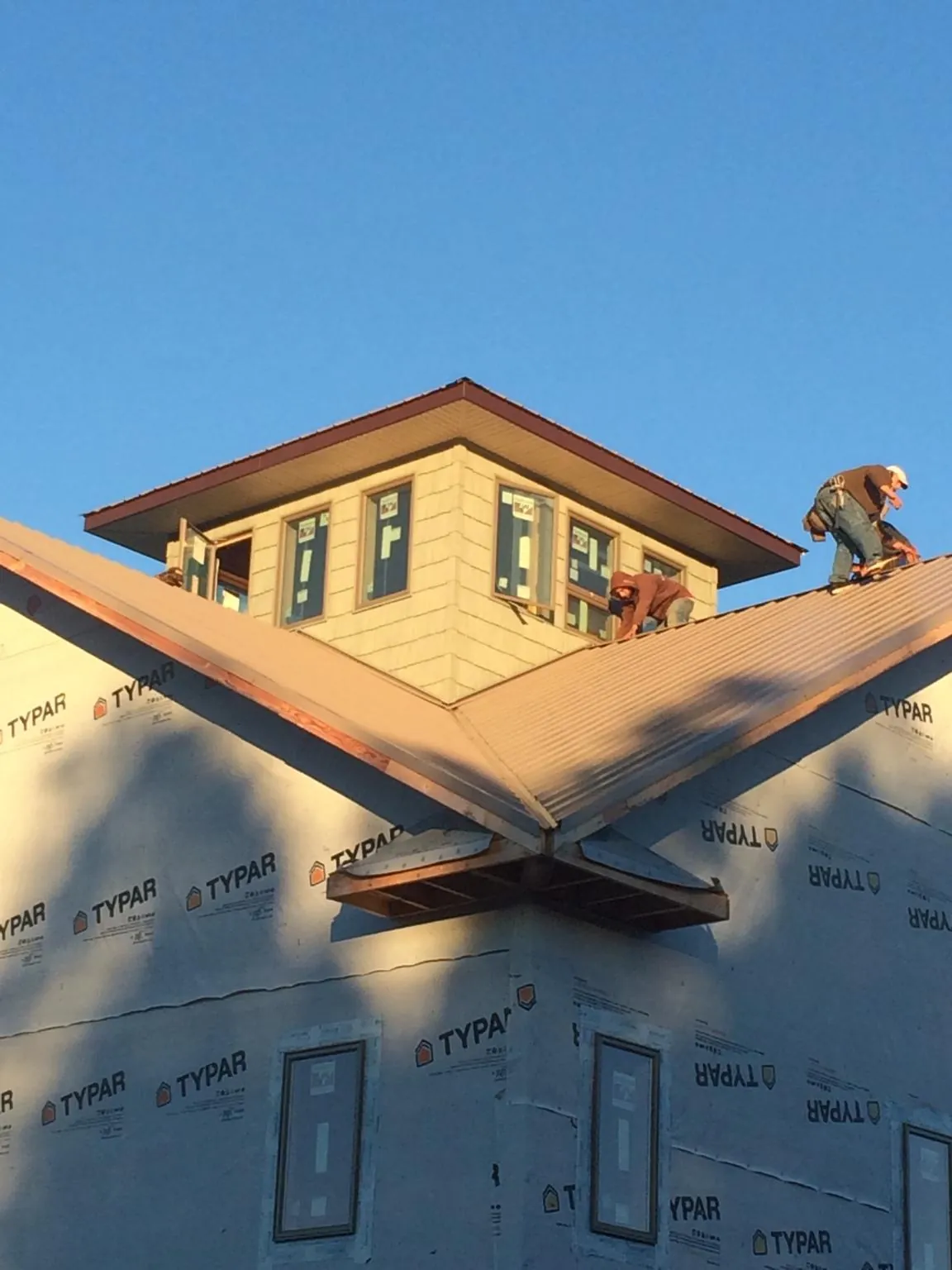 Roofers working around a rooftop cupola on a new metal roof at sunset — Roof Waterproofing in Swan by Roofing Brothers